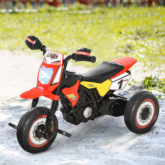 Red and yellow toy motorcycle on a snowy surface with grass in the background