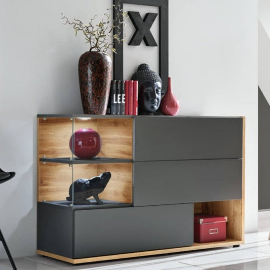 A modern sideboard cabinet with a mix of closed and open compartments, finished with LED lighting, in a pearl grey color, with decorative items displayed on top.