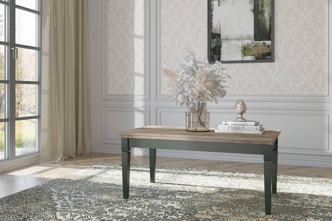 A rectangular coffee table with a green base and Oak Lefkas wooden top, placed on a patterned rug. The table is accompanied by decorative items and placed against a wall with a window, showcasing a room with elegant interior decor.
