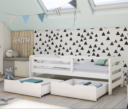 Children's room with a white bed, storage drawers, and decorative elements.
