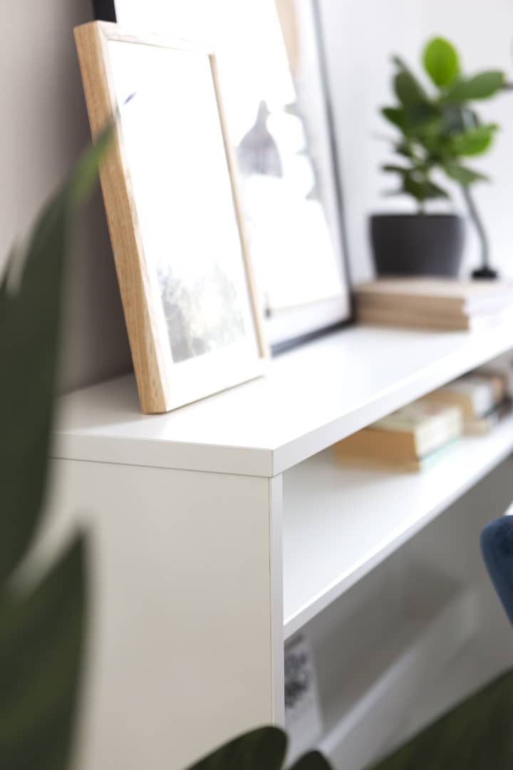 White shelf with a framed picture and books, blurred background