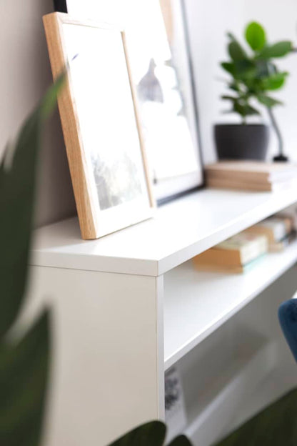 White shelf with a framed picture and books, blurred background
