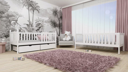 Children's room with white crib, gray chair, and pink rug in a room with palm tree wallpaper.
