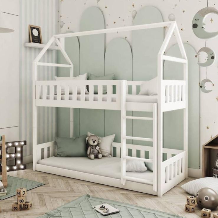 White children's house-shaped bed in a room with decorative elements.