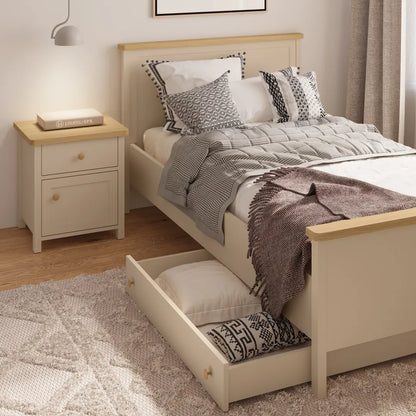 Beige bedroom with wooden bed and nightstand, featuring pillows and a blanket.