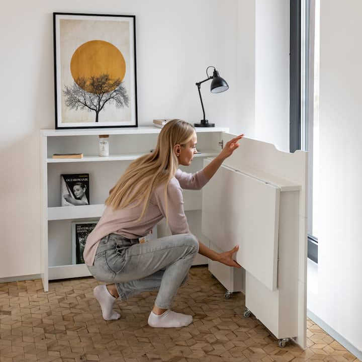 Woman in a modern home office setting with a desk and bookshelf.