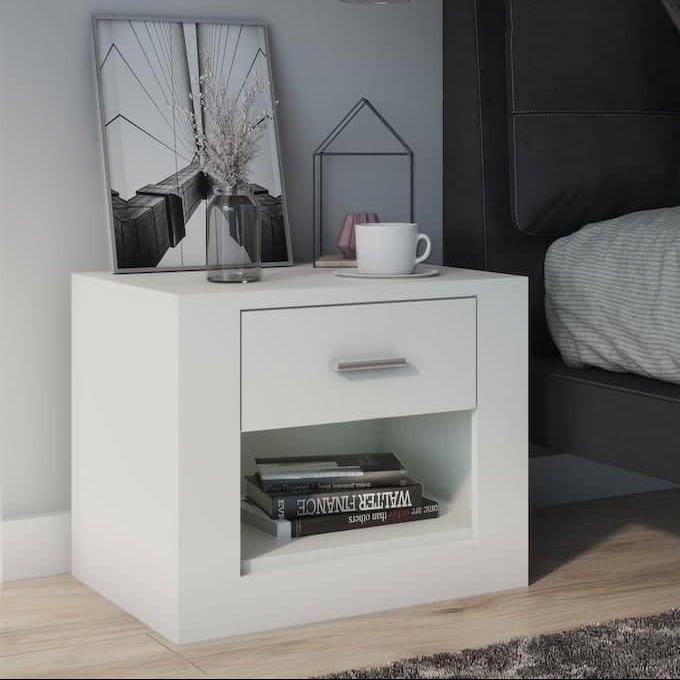 White nightstand next to a bed with gray bedding and pillows.