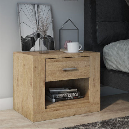 Wooden nightstand with a cup and books next to a bed with gray bedding.