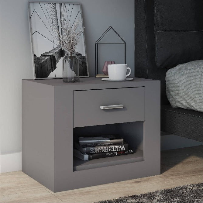 Gray nightstand next to a bed with gray bedding and pillows.
