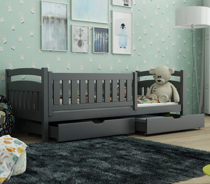 Gray children's bed with a teddy bear in a room with green walls and a window.